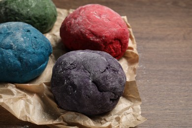 Photo of Dough painted with food colorings on wooden table, closeup