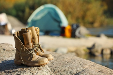 Photo of Boots on rock against blurred background. Space for text