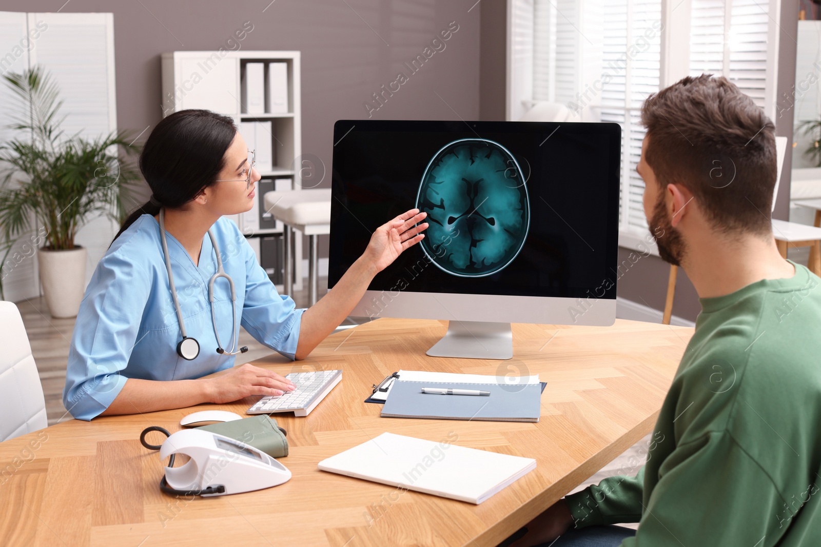 Photo of Neurologist showing brain scan to patient in clinic