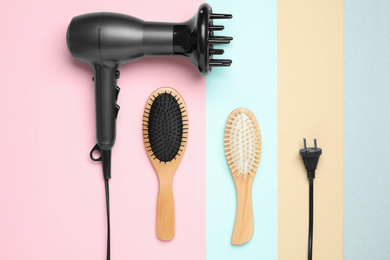 Hair dryer and different brushes on color background, flat lay. Professional hairdresser tool