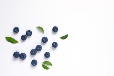 Photo of Tasty fresh blueberries with green leaves on white background, flat lay. Space for text