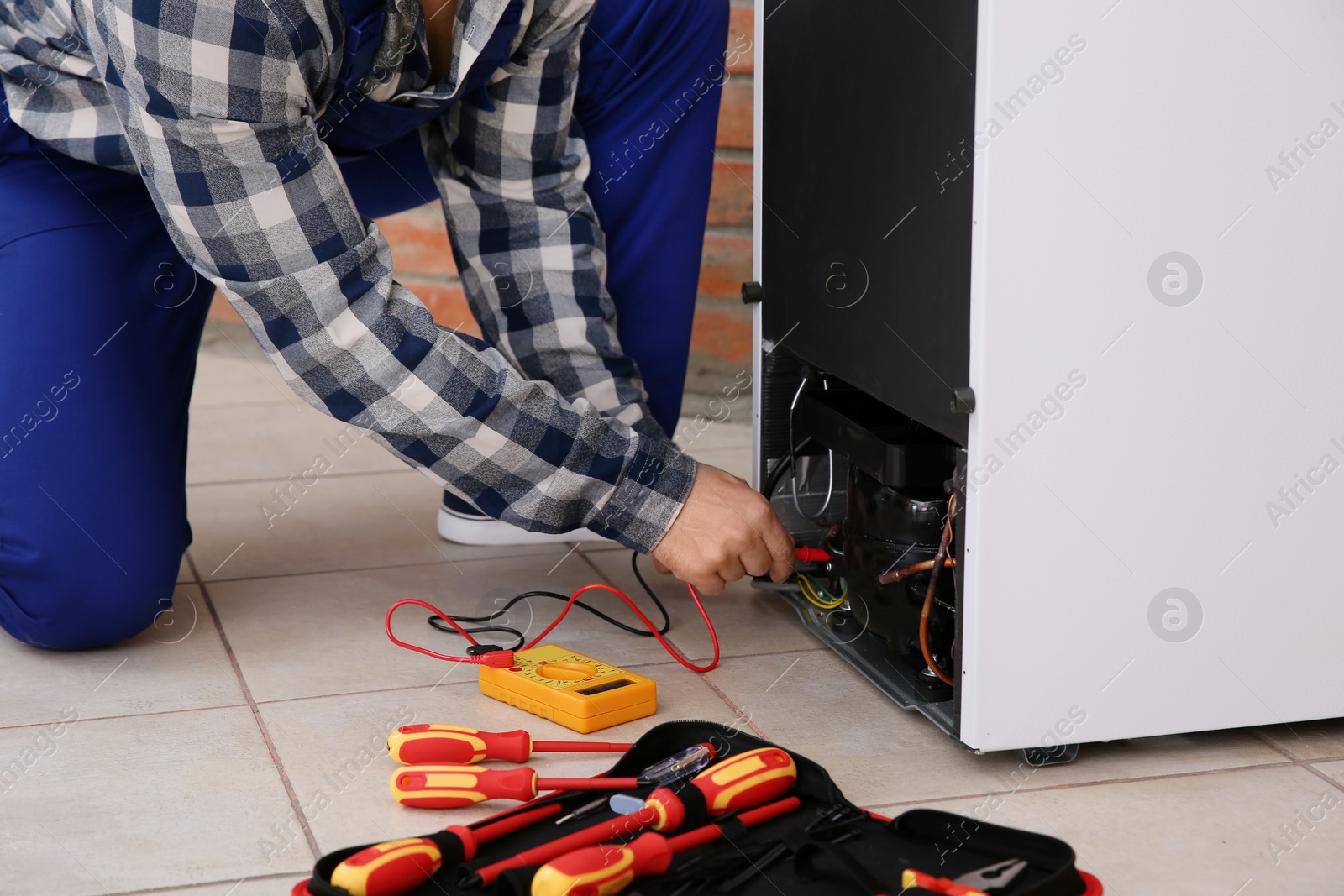 Photo of Male technician repairing broken refrigerator indoors, closeup