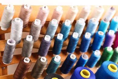 Photo of Set of colorful threads on stand, closeup. Dressmaking equipment