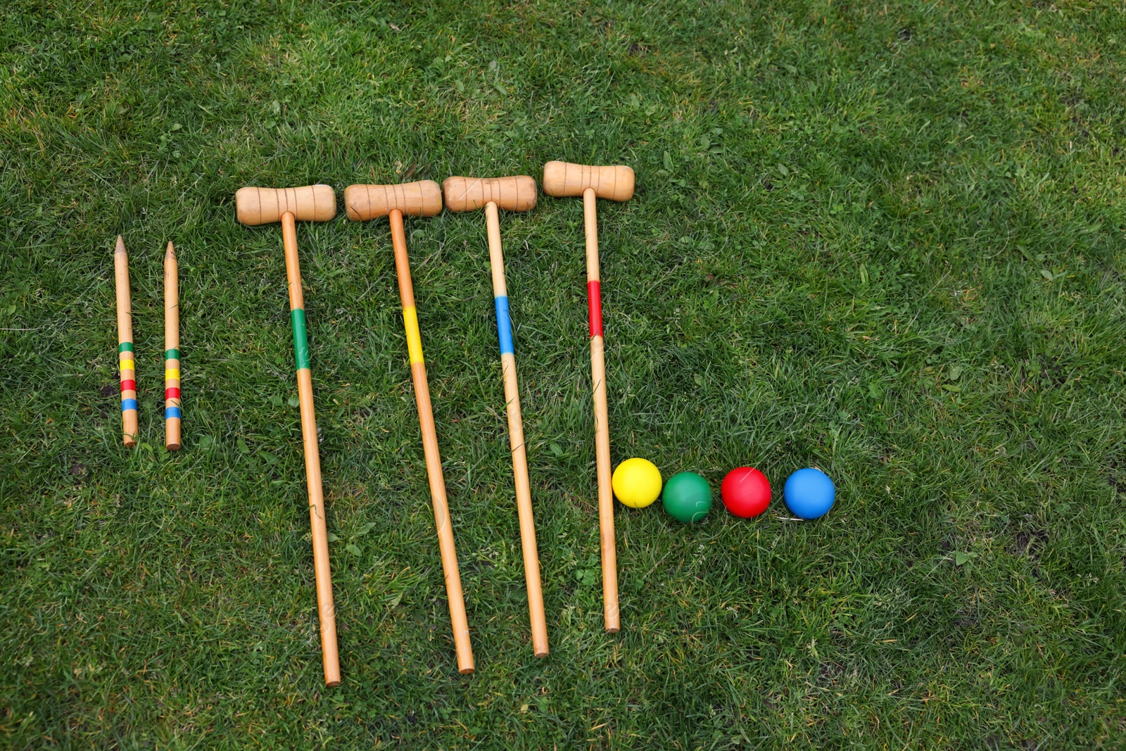 Photo of Set of croquet equipment on green grass, flat lay