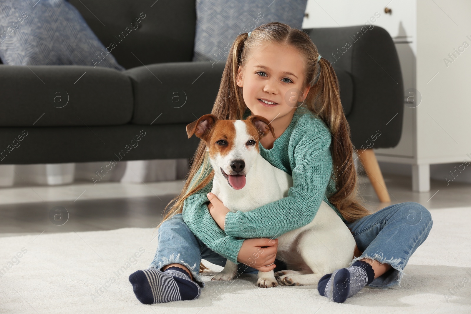 Photo of Cute girl hugging her dog on floor at home. Adorable pet