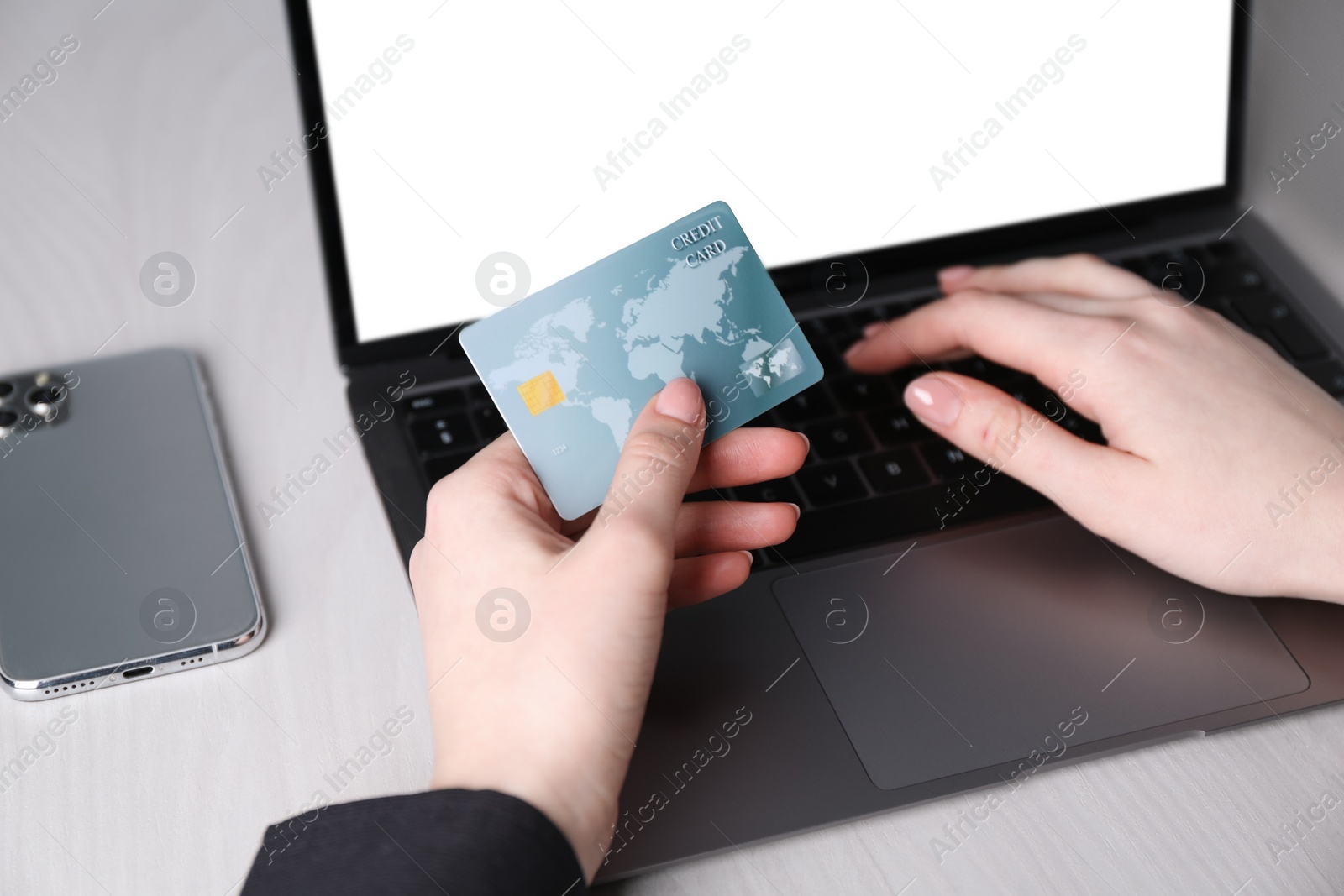 Photo of Online payment. Woman with laptop and credit card at white wooden table, closeup