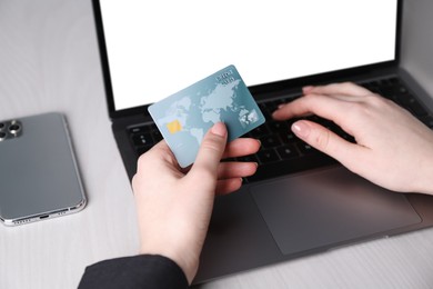 Photo of Online payment. Woman with laptop and credit card at white wooden table, closeup