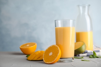 Fresh mango drink and tropical fruits on table against color background. Space for text