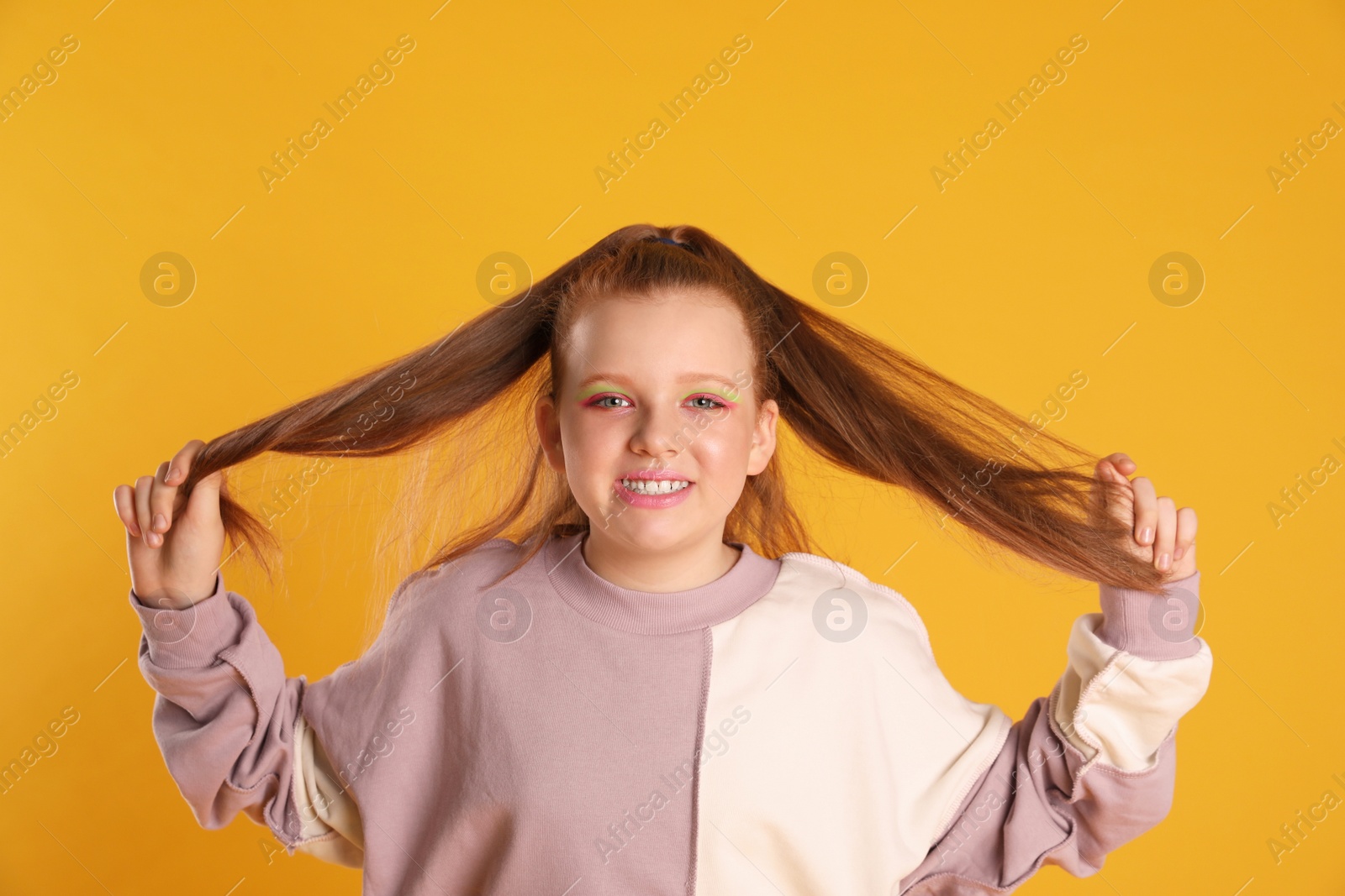 Photo of Cute indie girl with bright makeup on yellow background