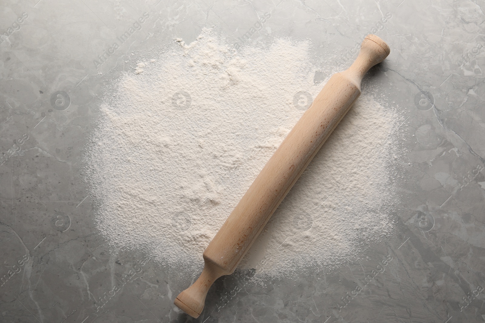 Photo of Pile of flour and rolling pin on grey marble table, top view