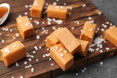 Photo of Delicious caramel candies with salt on wooden board