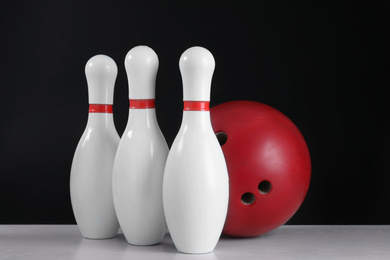 Photo of Red bowling ball and pins on grey table