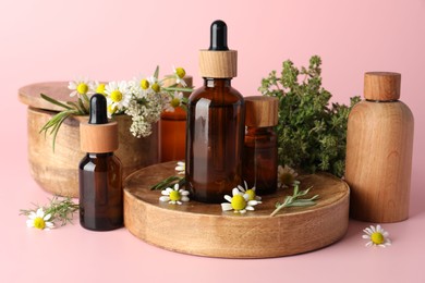 Aromatherapy. Different essential oils and flowers on pink background