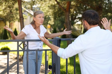 Photo of Emotional neighbours having argument near fence outdoors