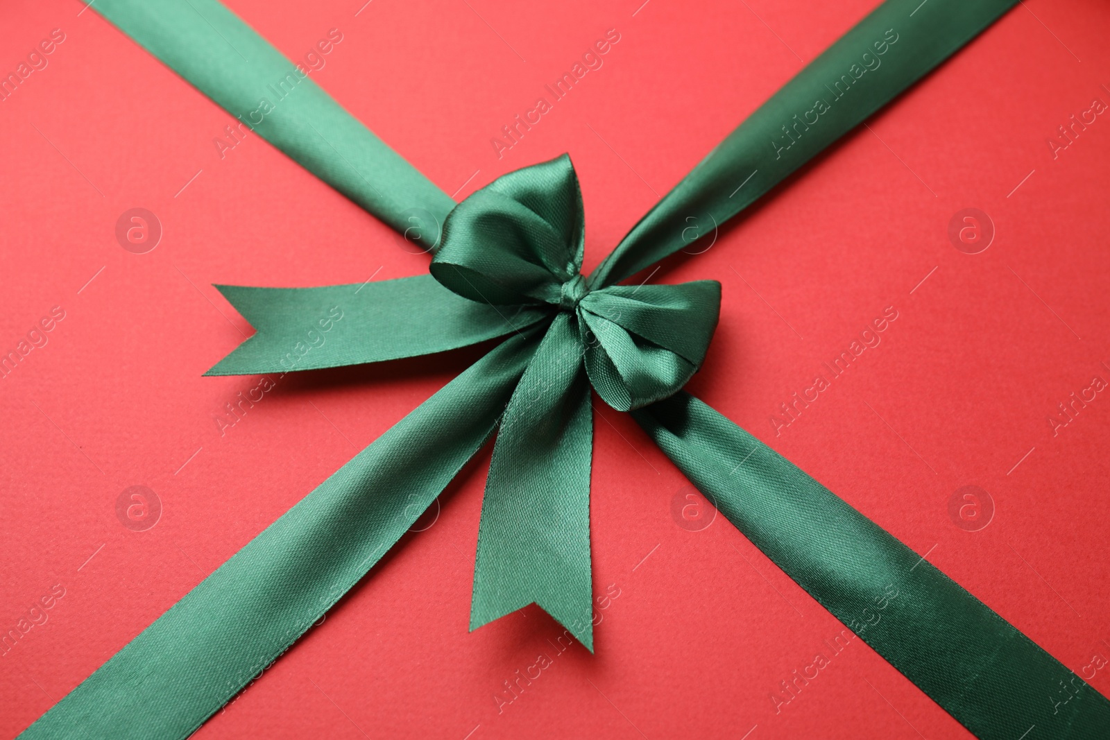 Photo of Green satin ribbon with bow on red background