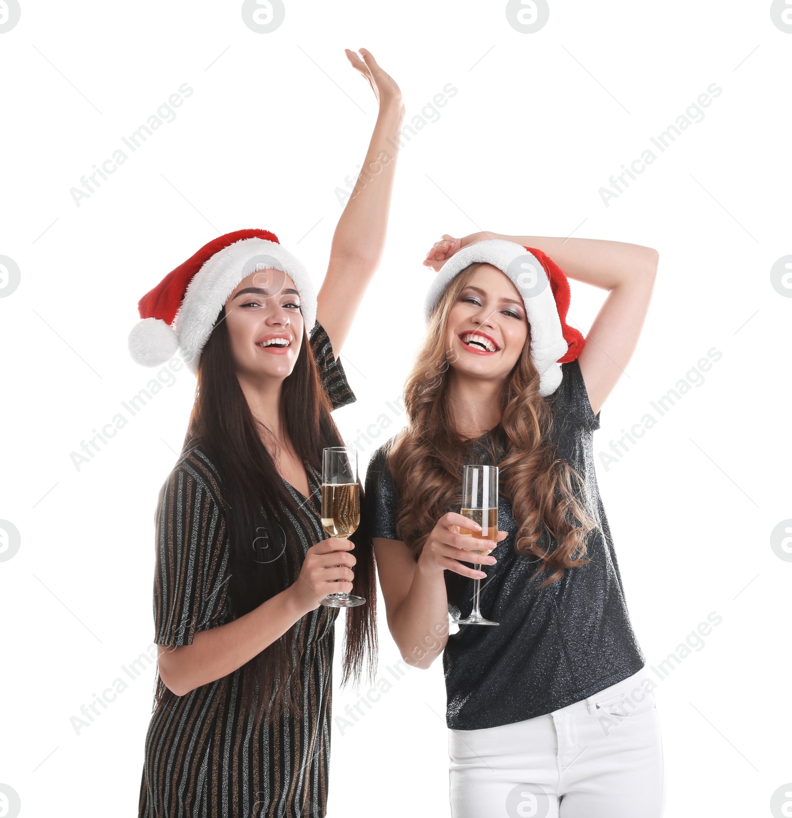 Photo of Beautiful young women in Santa hats with glasses of champagne on white background. Christmas celebration