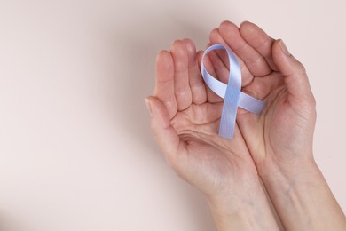 International Psoriasis Day. Woman with light blue ribbon as symbol of support on beige background, top view. Space for text