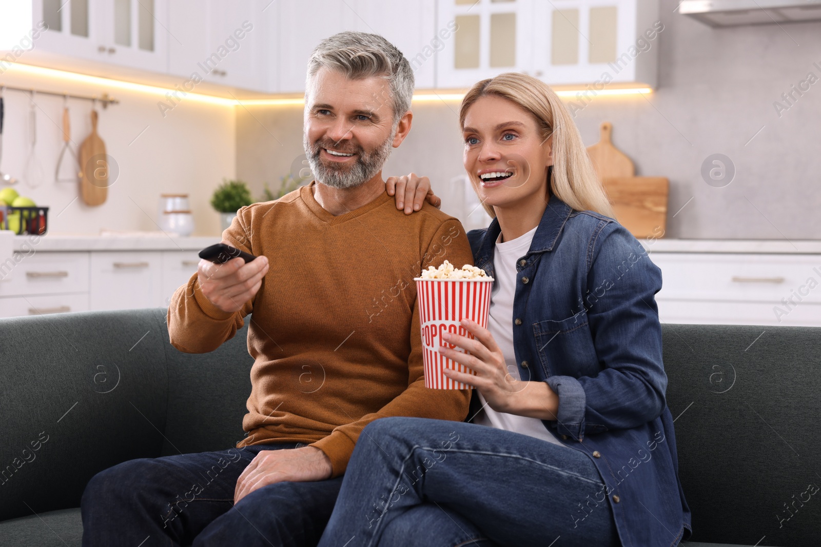 Photo of Happy affectionate couple with popcorn spending time together on sofa at home. Romantic date