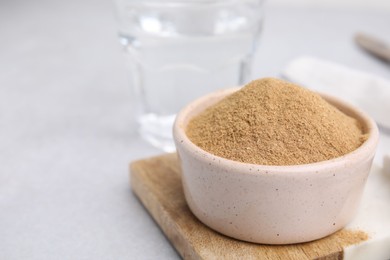 Photo of Dietary fiber. Psyllium husk powder in bowl on light grey table, closeup. Space for text