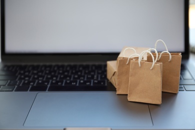 Internet shopping. Small bags and boxes on modern laptop, space for text