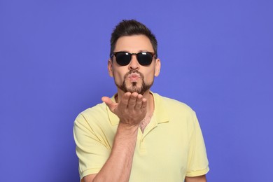 Photo of Handsome man blowing kiss on violet background