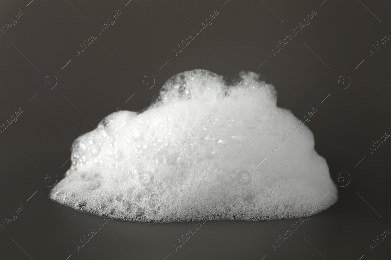 Photo of Fluffy bath foam on grey background, closeup