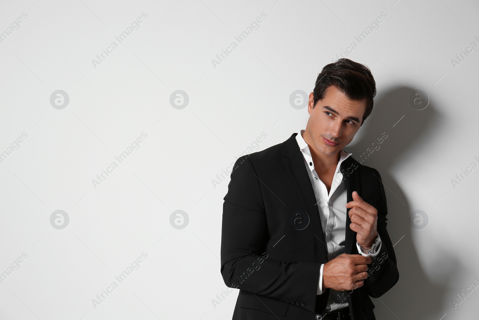 Photo of Handsome young man in elegant suit on light beige background. Space for text