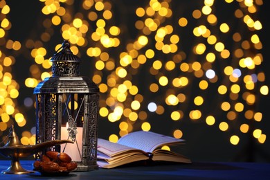 Photo of Arabic lantern, Quran, dates and Aladdin magic lamp on table against blurred lights at night. Space for text