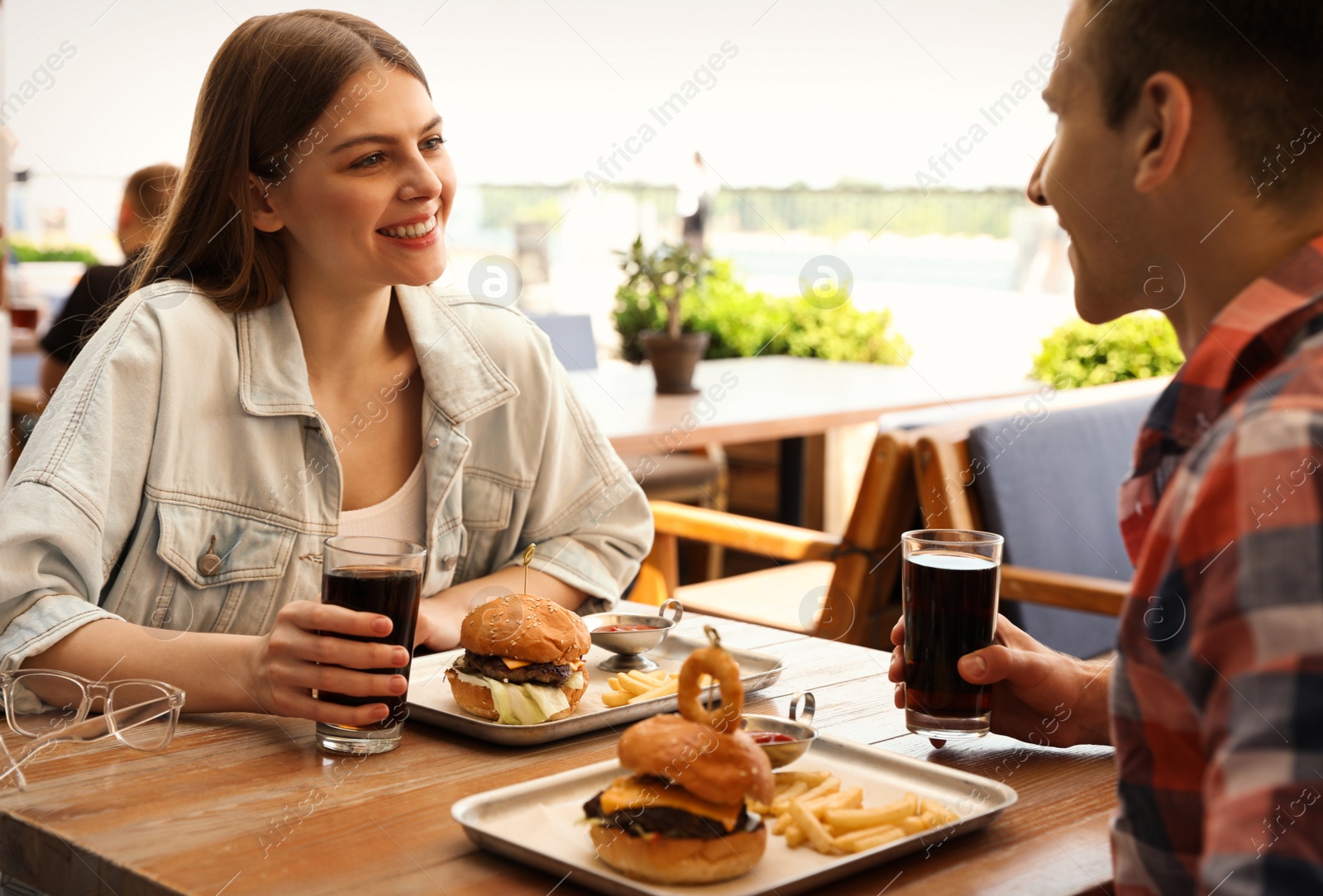 Photo of Young happy couple with burgers in street cafe