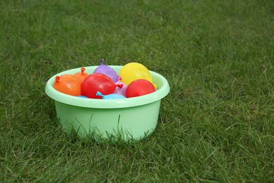 Photo of Basin full of water bombs on green grass. Space for text