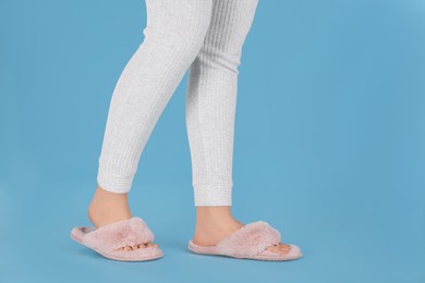 Photo of Woman in fluffy slippers on light blue background, closeup