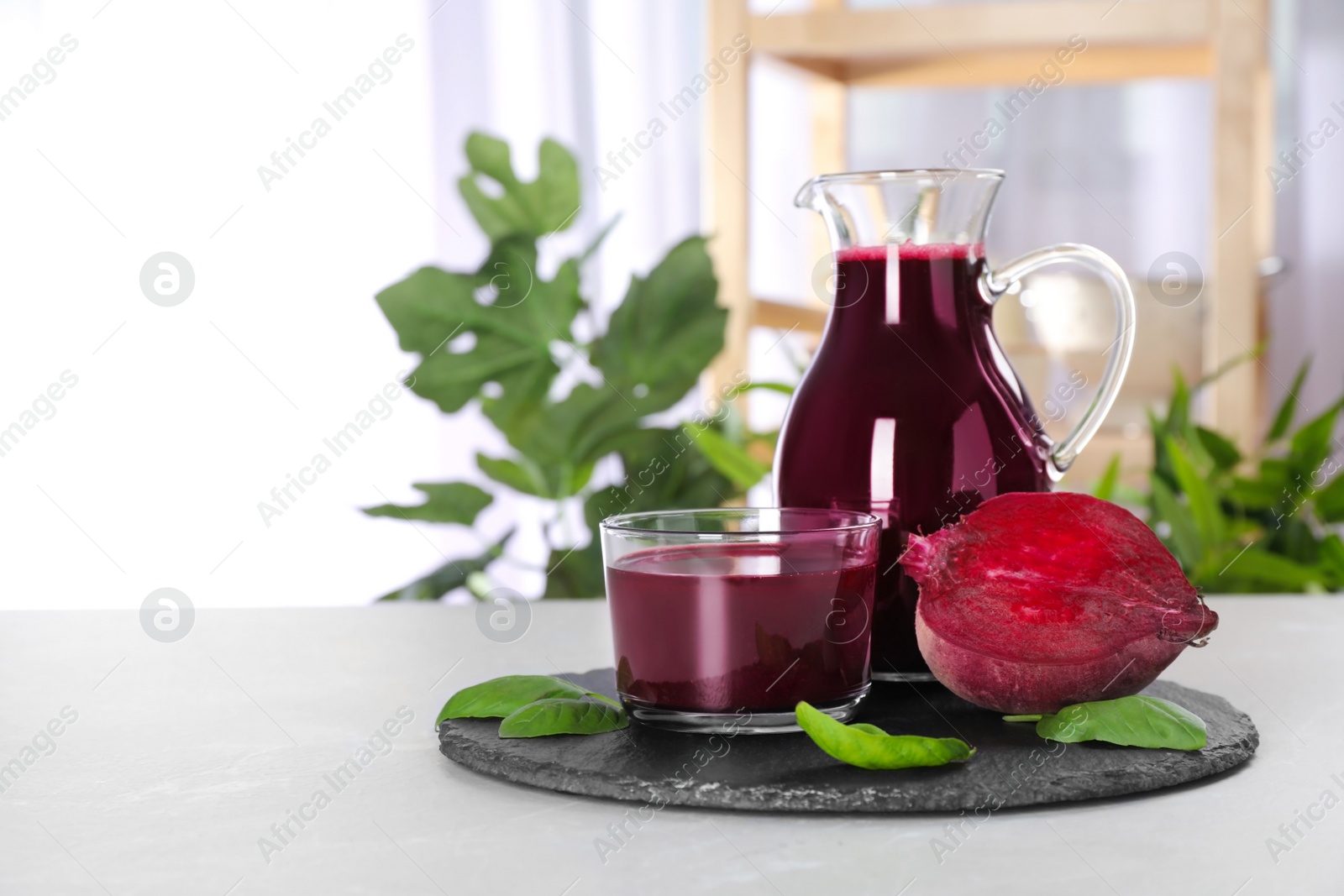 Photo of Jug and glass of fresh beet juice on table