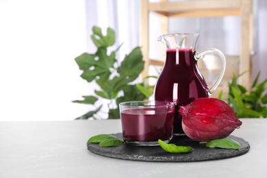 Photo of Jug and glass of fresh beet juice on table