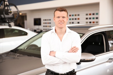 Portrait of young salesman in car dealership