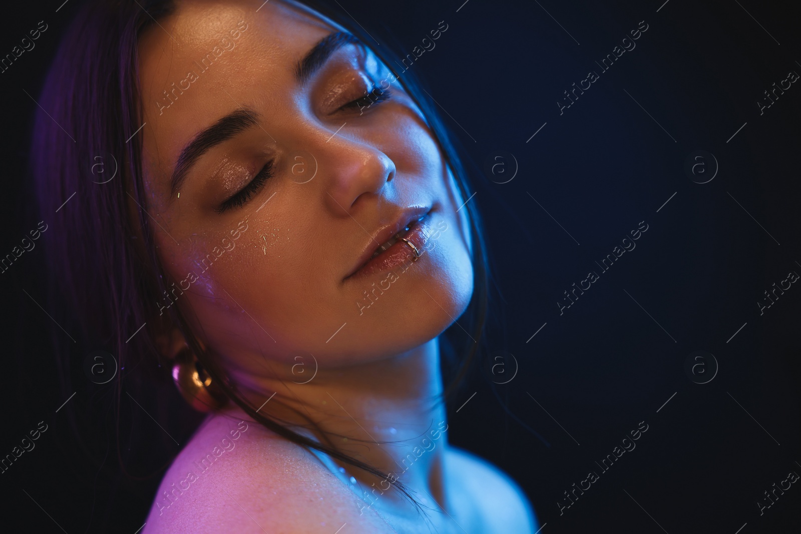 Photo of Portrait of beautiful woman on dark background in neon lights, space for text