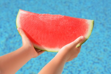 Child holding fresh juicy watermelon near swimming pool outdoors, closeup