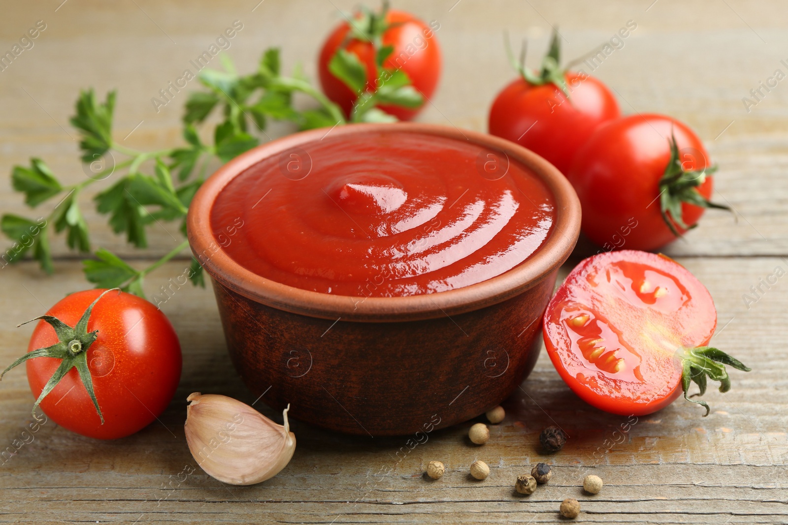 Photo of Tasty ketchup, fresh tomatoes, parsley and spices on wooden table