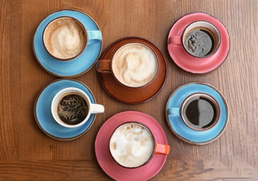 Cups of fresh aromatic coffee on wooden table, top view