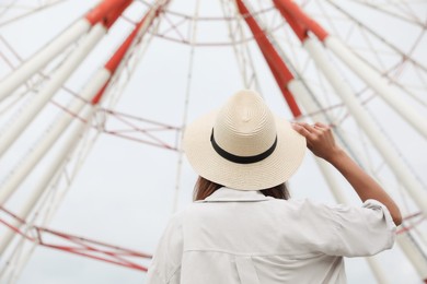 Photo of Young woman near Ferris wheel outdoors, back view