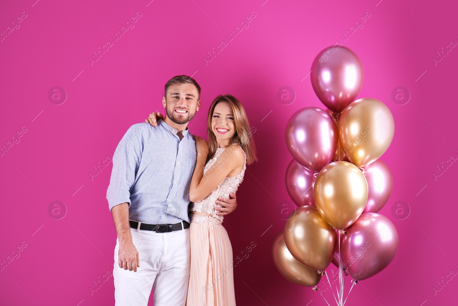 Photo of Young couple with air balloons on color background