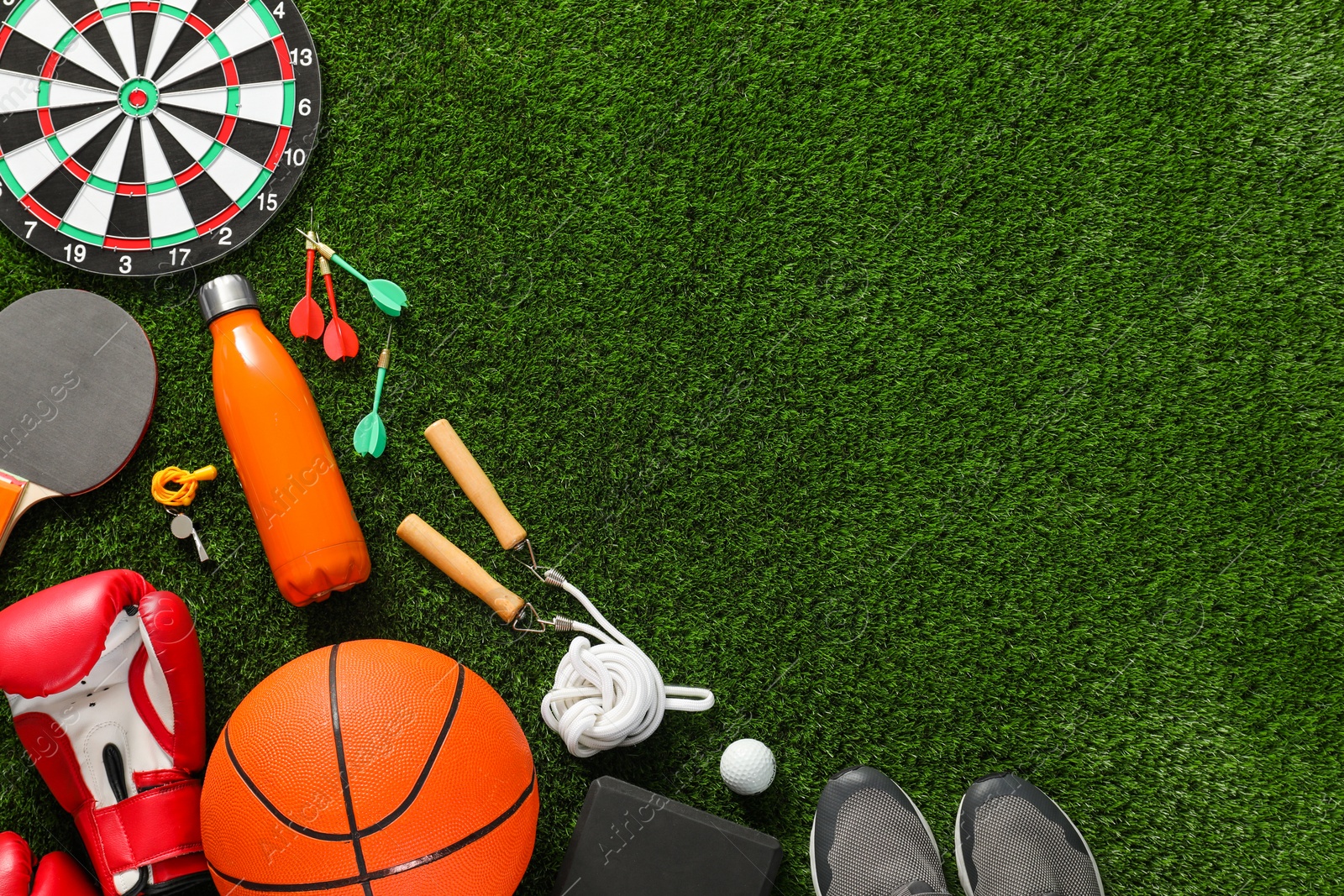 Photo of Different sport equipment on green grass, flat lay. Space for text