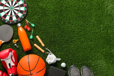 Photo of Different sport equipment on green grass, flat lay. Space for text