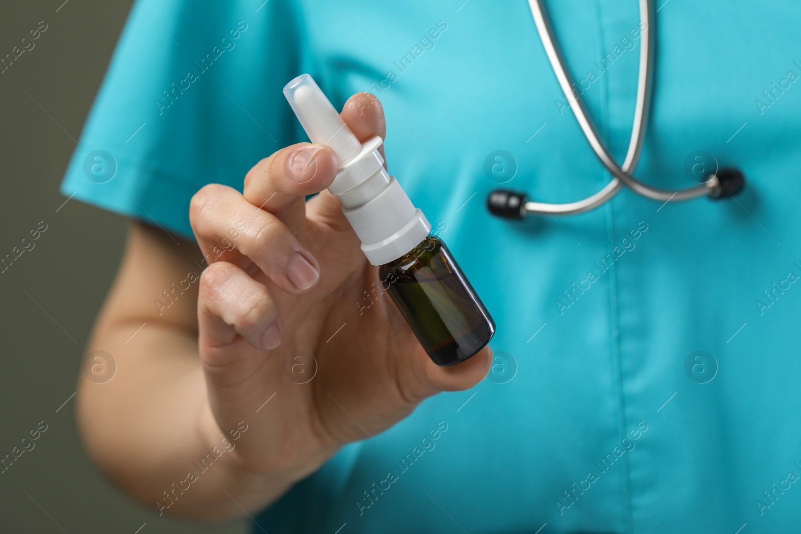 Photo of Woman holding nasal spray bottle on olive background, closeup