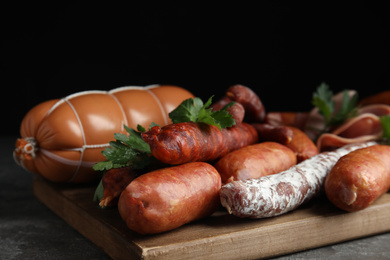 Different tasty sausages on wooden board, closeup