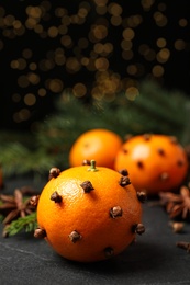 Photo of Delicious fresh tangerines with cloves on black table. Christmas celebration