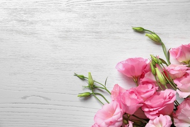 Flat lay composition with beautiful Eustoma flowers on light wooden background