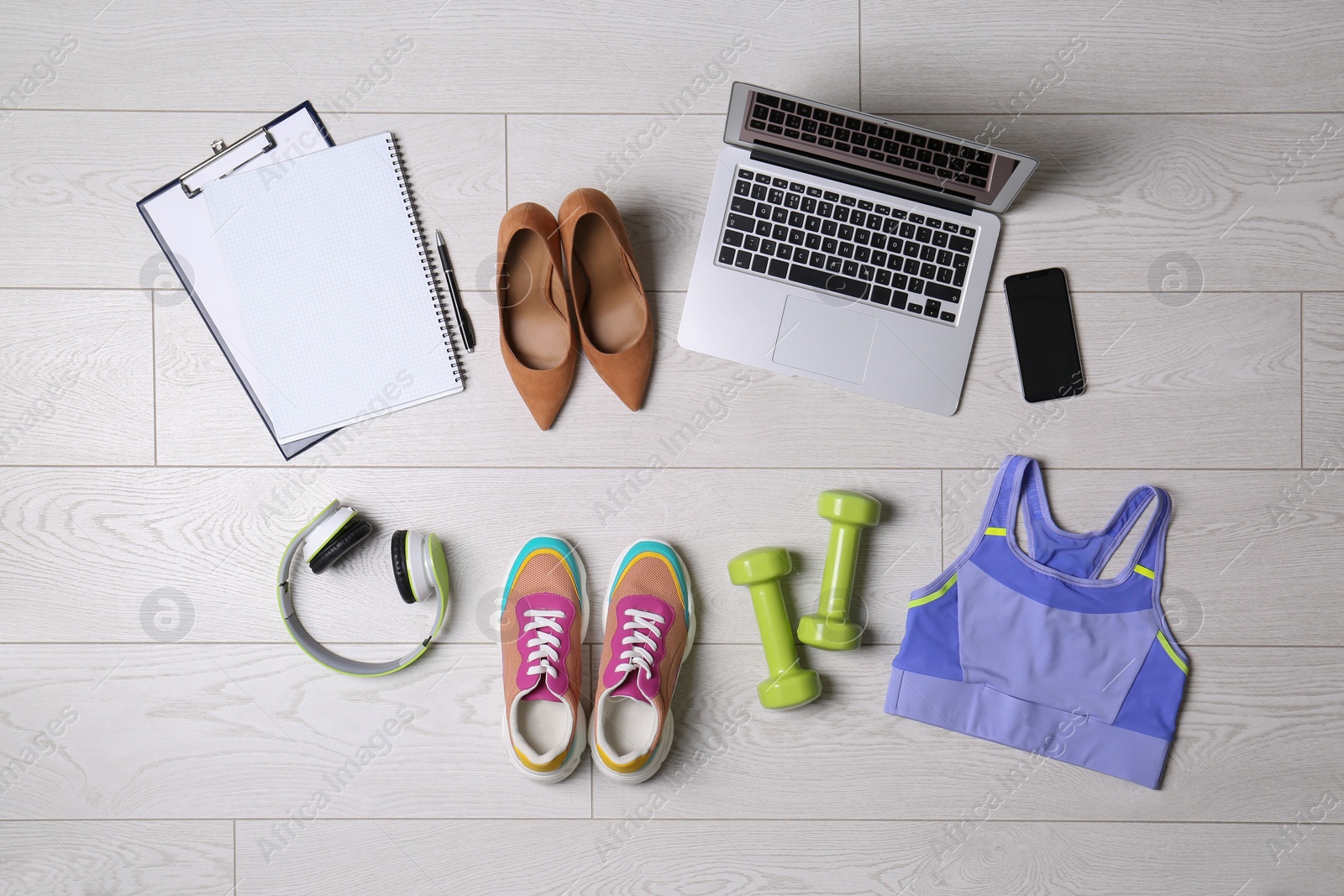 Photo of Flat lay composition with business supplies and sport equipment on white wooden floor. Concept of balance between work and life