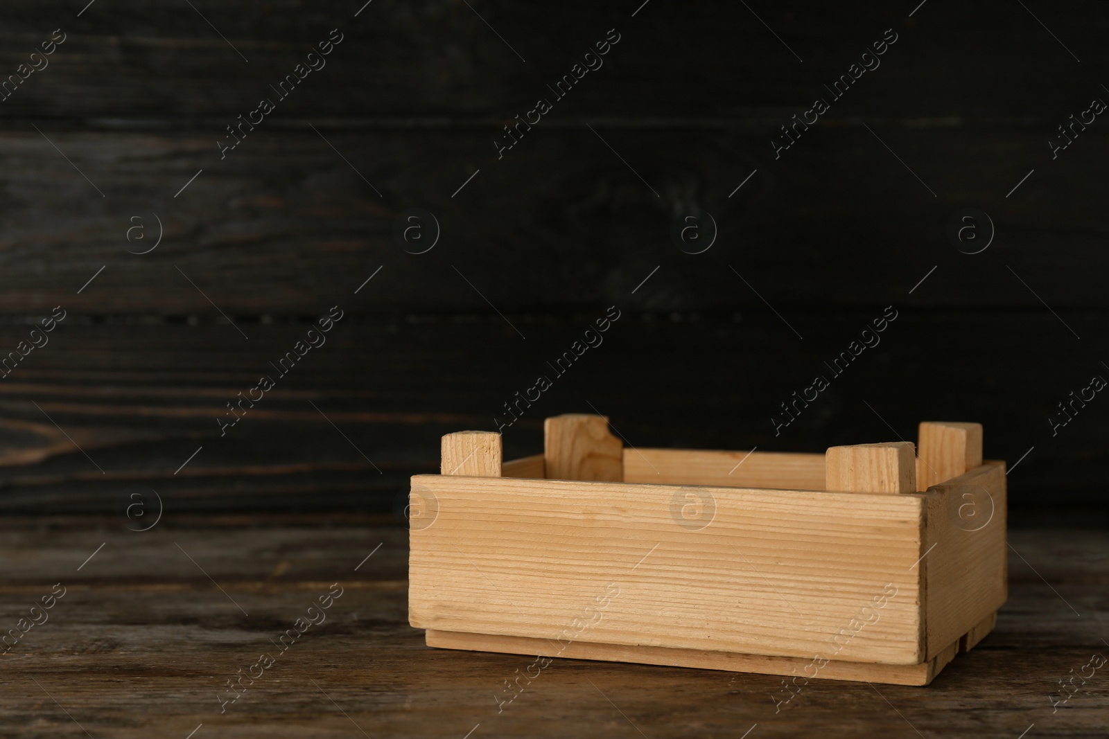 Photo of Wooden crate on table against dark background. Space for text