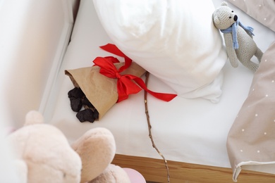 Photo of Wrapped lumps of coal and tree twig under pillow in children's bed. St. Nicholas Day