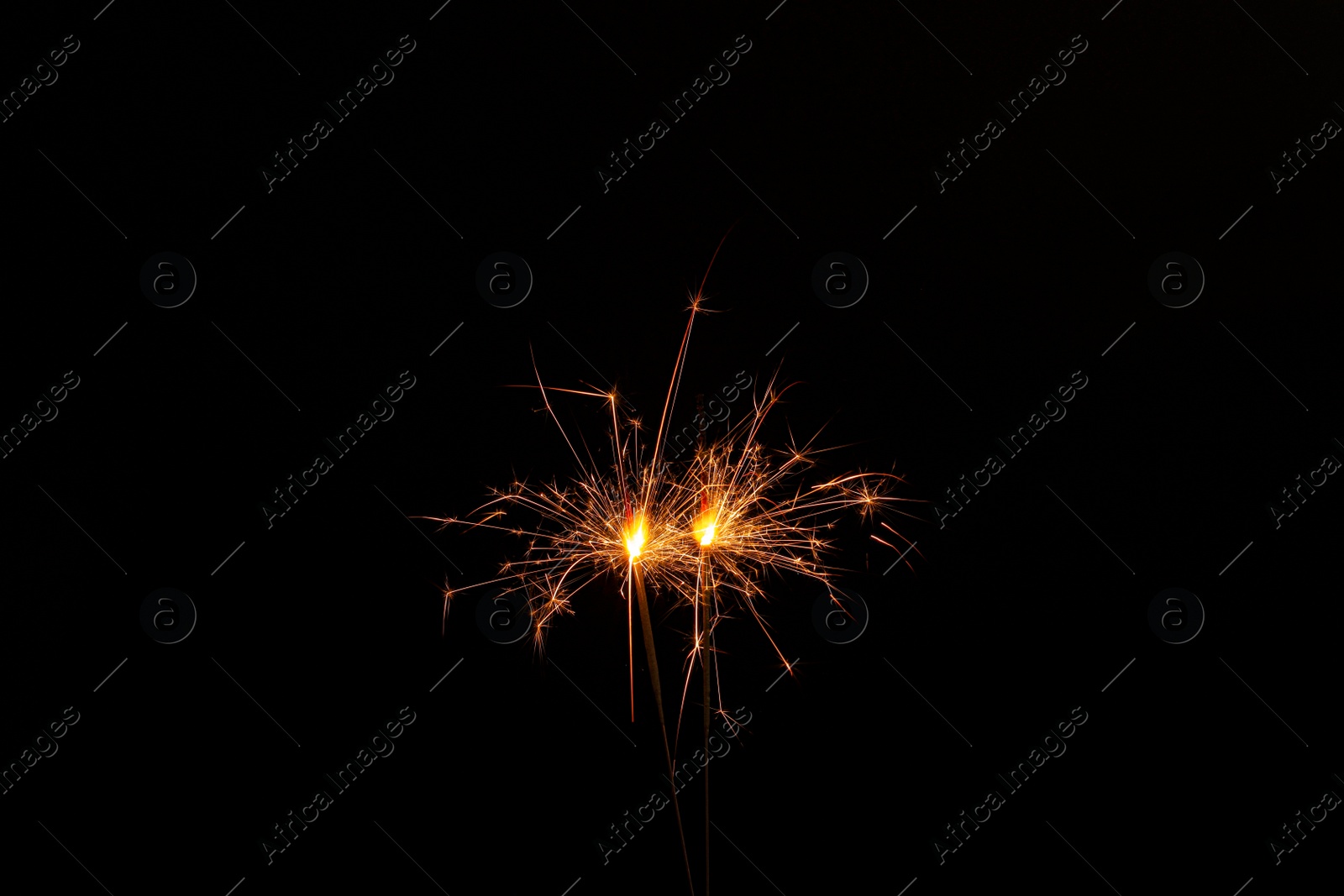 Photo of Two burning sparkler sticks glowing in dark